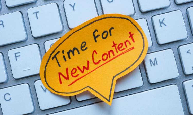 a keyboard with a a post it reading "time for new content!"
